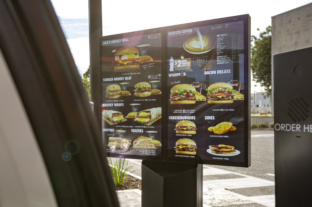 Woman driving car ordering MacDonald's via drive-thru solution powered by Coates Group.